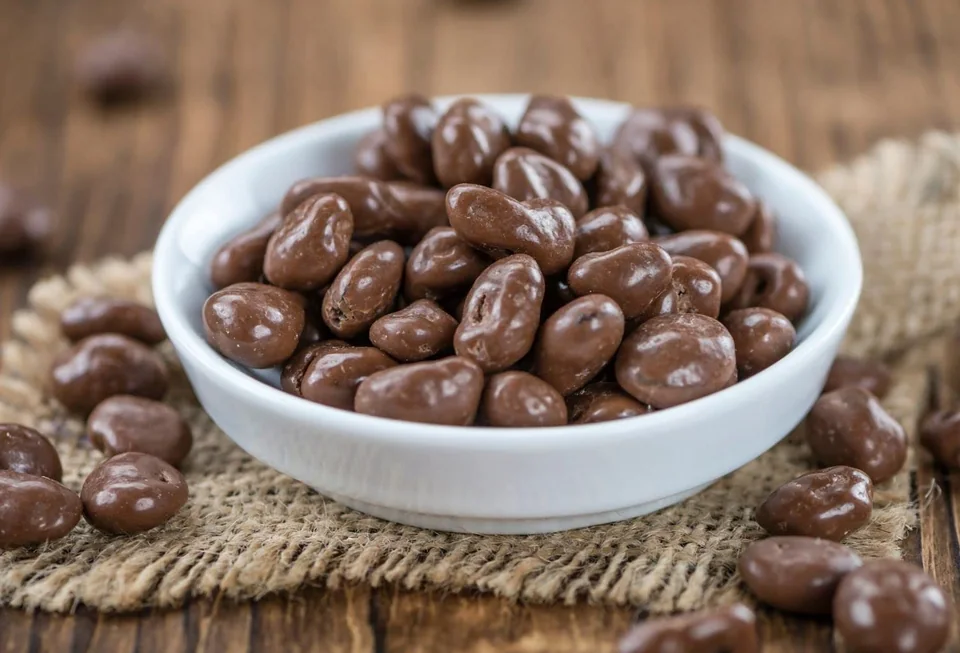 A white bowl of milk chocolate covered raisins on burlap